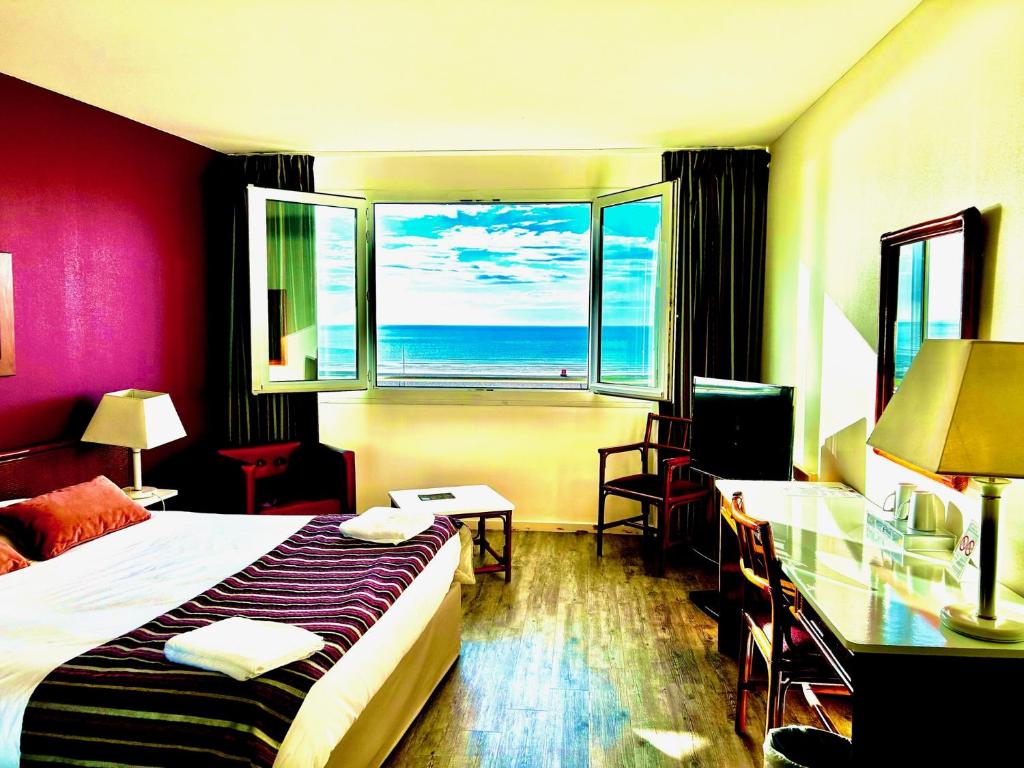 a hotel room with a bed and a view of the ocean at Hotel de l&#39;Europe in Dieppe