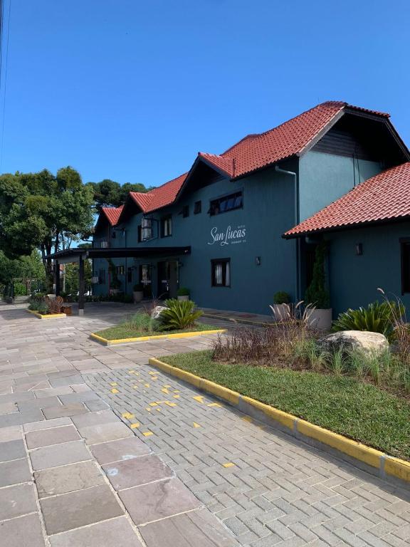 a blue building with a red roof on a street at Hotel San Lucas in Gramado