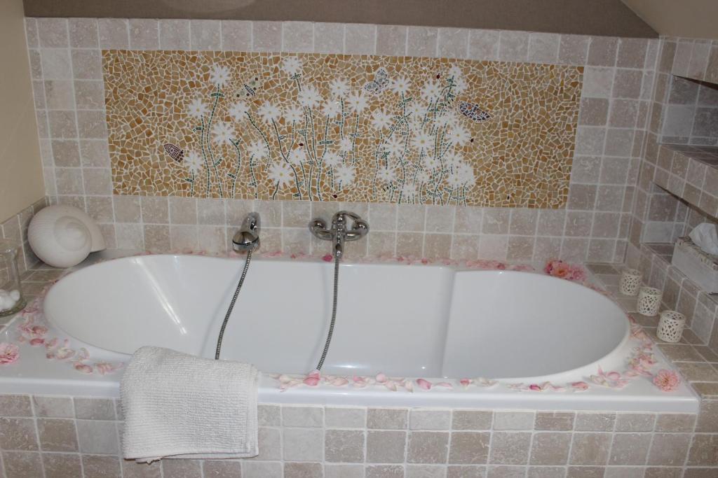 a bath tub in a bathroom with a tile wall at Moulin De Larcy in Ribérac