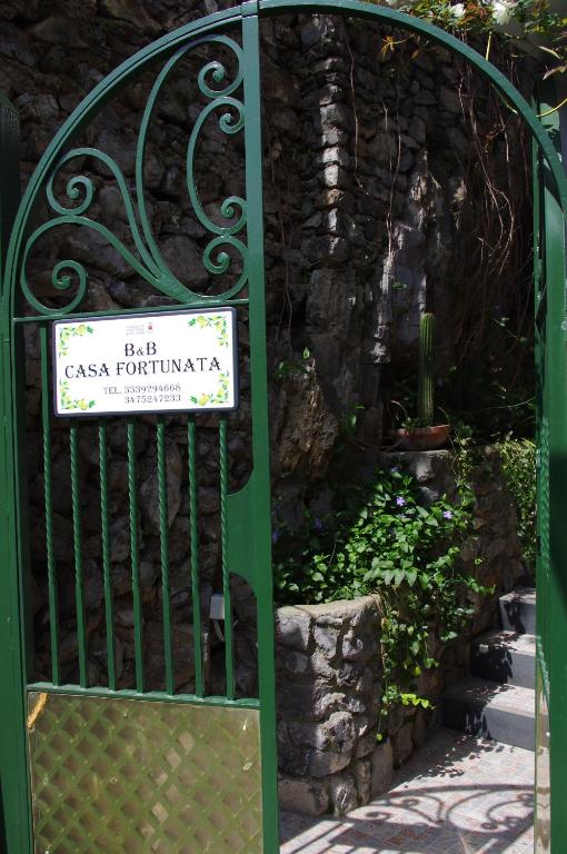 a green gate with a sign in a garden at Casa Fortunata in Positano