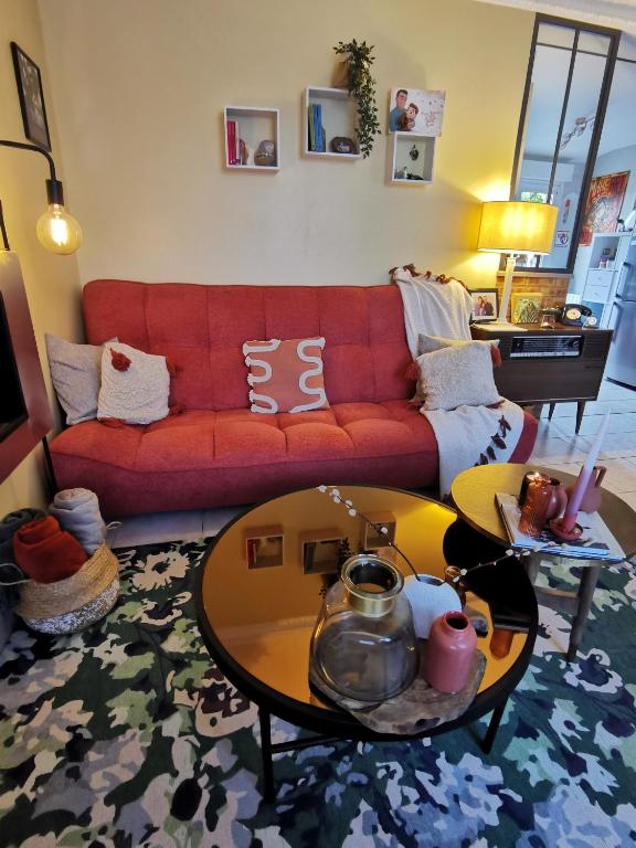 a living room with a red couch and a table at Maison Acacias Le Mans in Le Mans