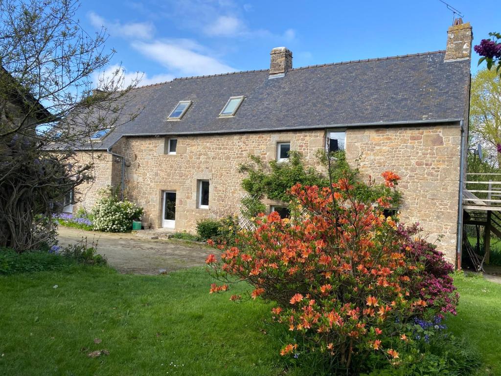Une vieille maison en briques avec des fleurs dans la cour dans l'établissement Gite de la Ville aux Bois, à Parigné