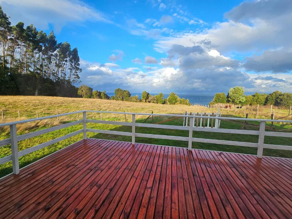 a wooden deck with a fence and the ocean at Cabaña en Chacao Viejo, Chiloé - Tranquilidad y Frente al mar in Ancud
