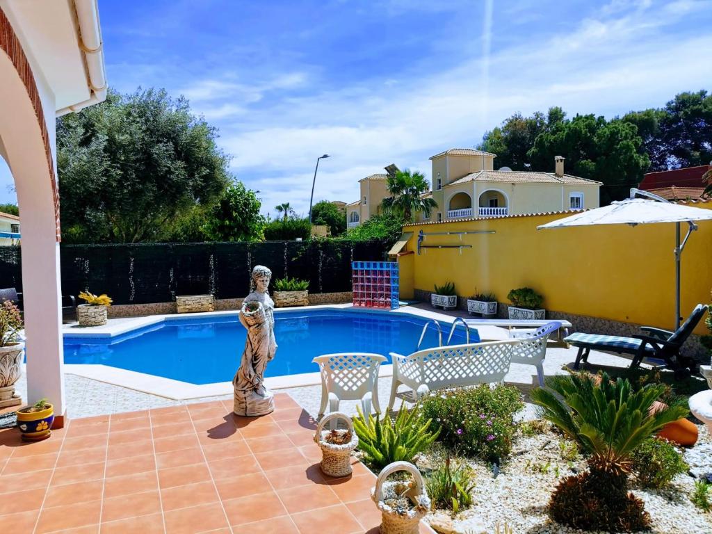 a patio with a pool and a statue next to a house at Villa SIA in Torrevieja