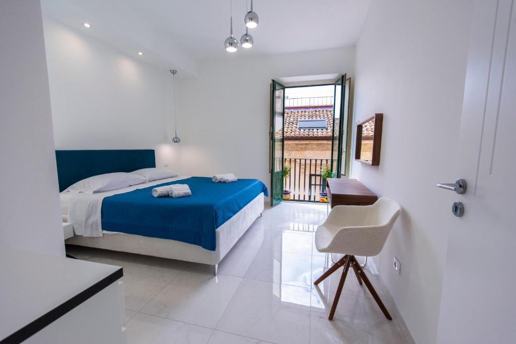 una camera con un letto blu e una sedia di Kapitano Apartments a Taormina