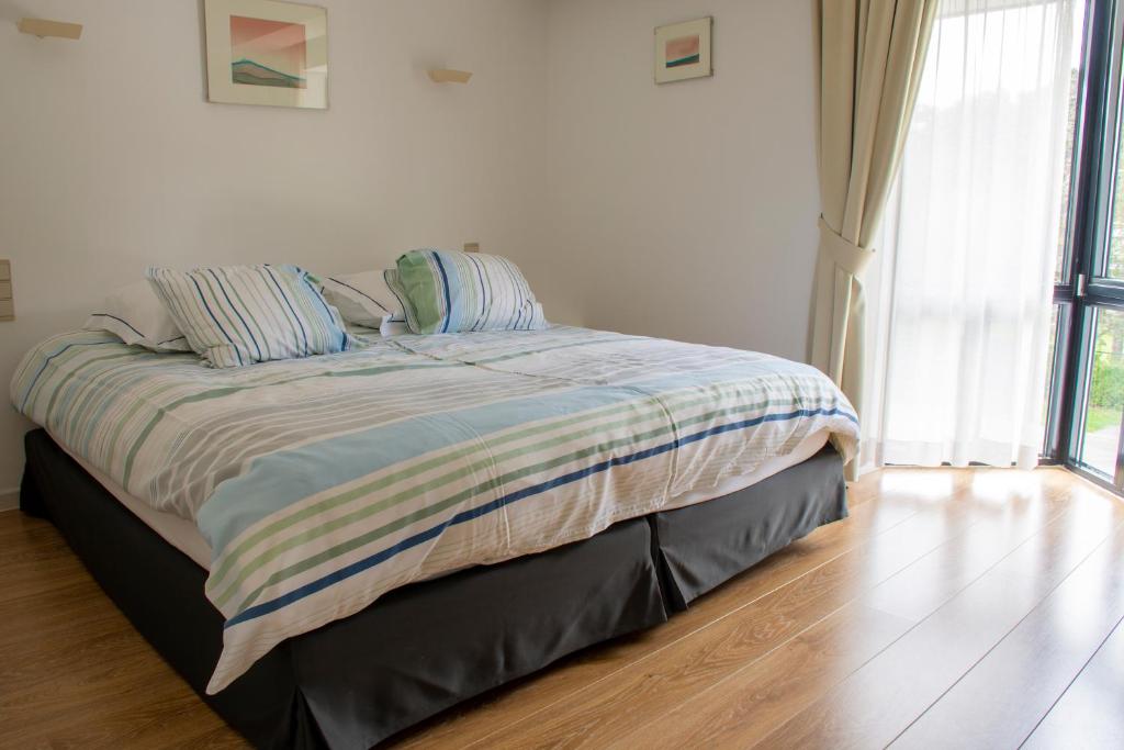 a bed in a white bedroom with a wooden floor at De Witte Meren in Keerbergen