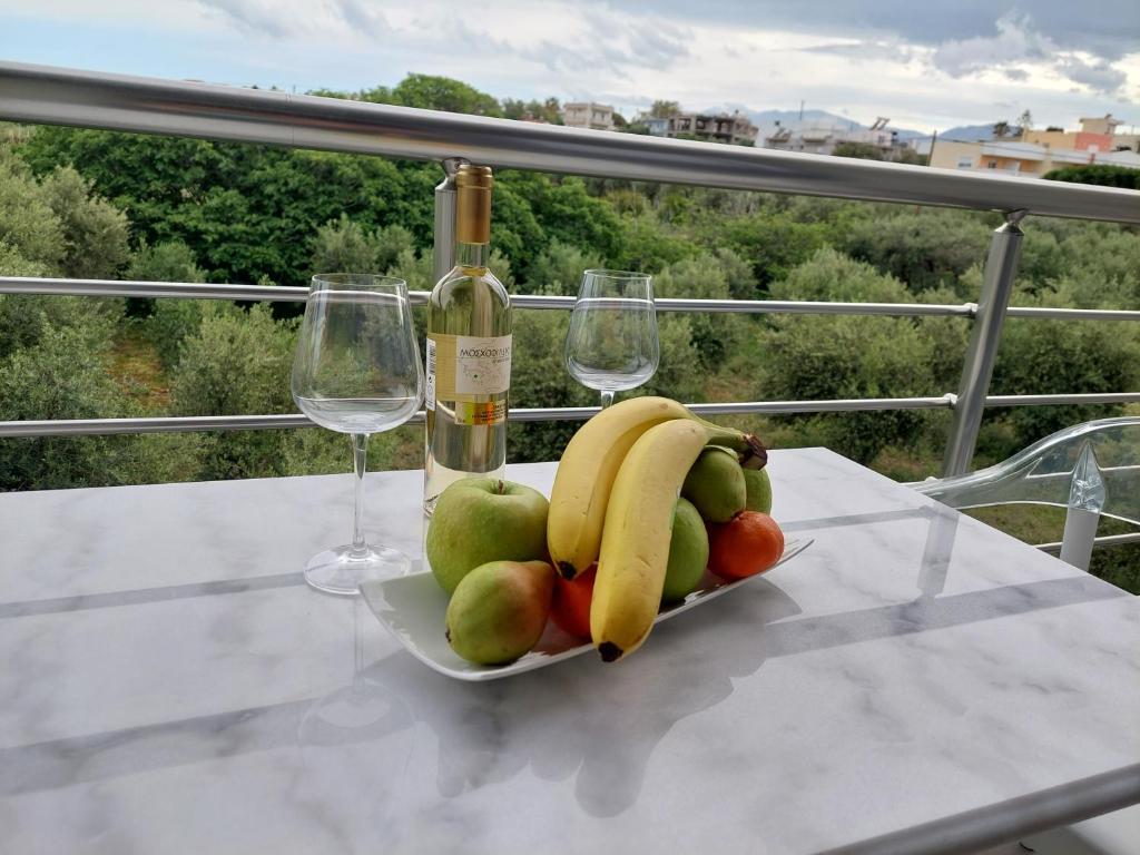 a bowl of fruit on a table with a bottle of wine at Luana Monte Apartments in Amoudara Herakliou