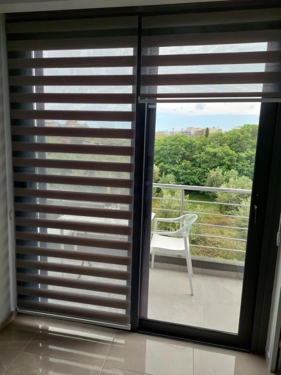 a room with a window with a chair on a balcony at Luana Monte Apartments in Amoudara Herakliou