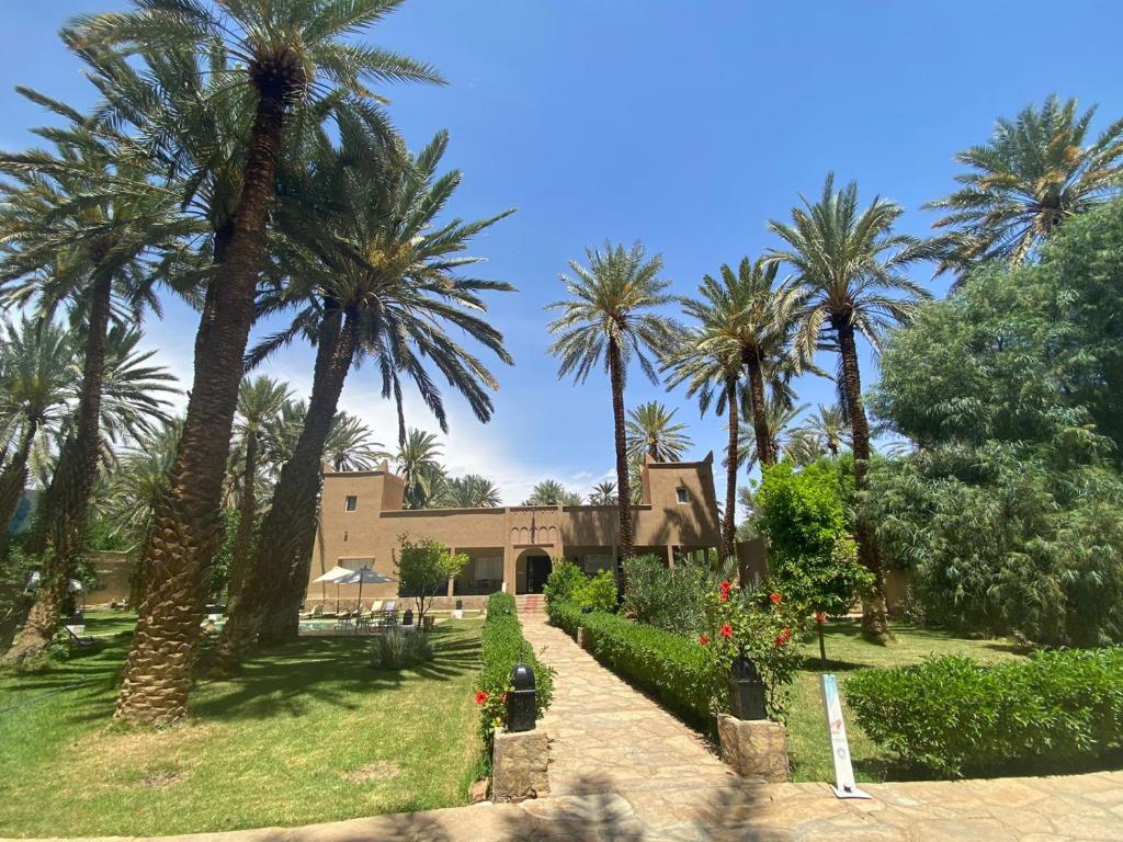 a resort with palm trees and a building at Maison d H&ocirc;te Ighrem in Goulmima