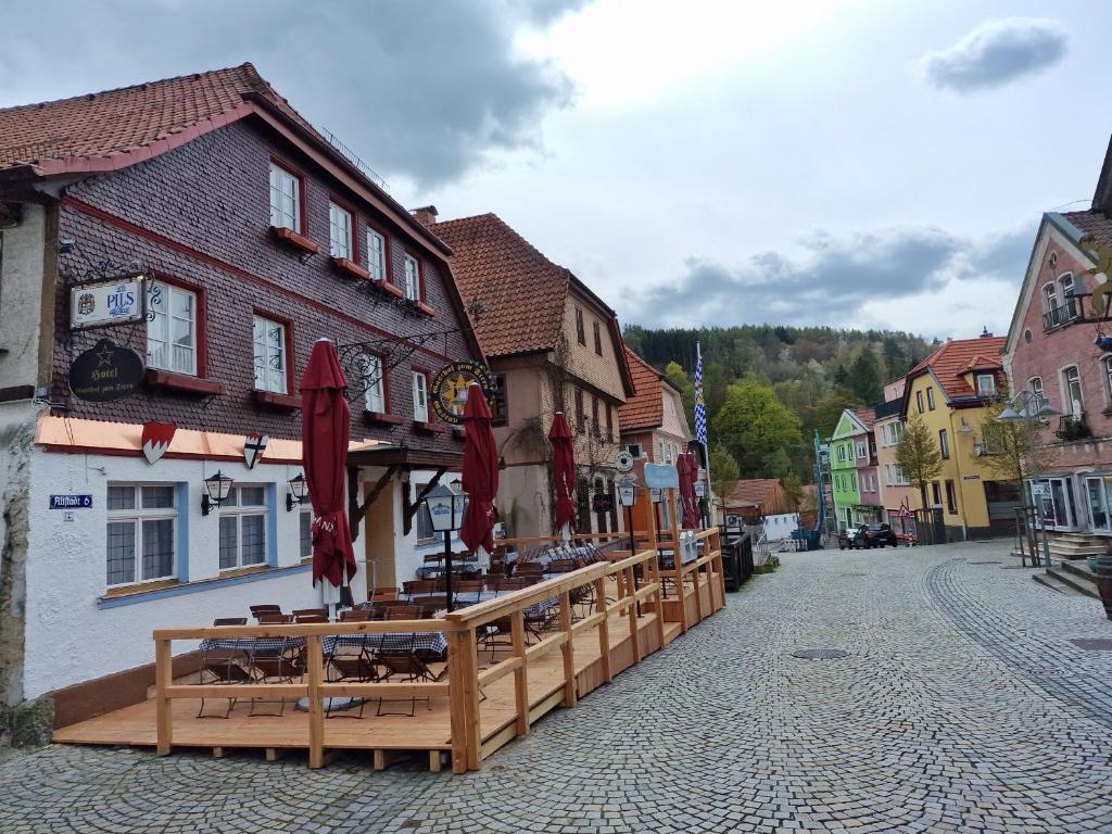 a town street with a restaurant with tables and umbrellas at Gasthof zum Stern in Bad Brückenau