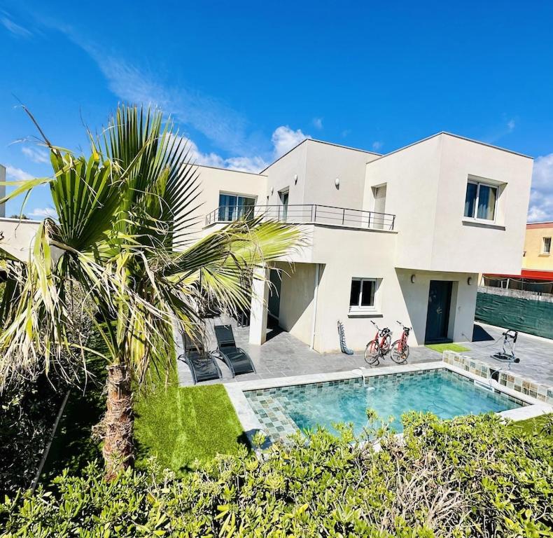 une maison avec un palmier et une piscine dans l'établissement Villa de Vinci Locasete, à Sète