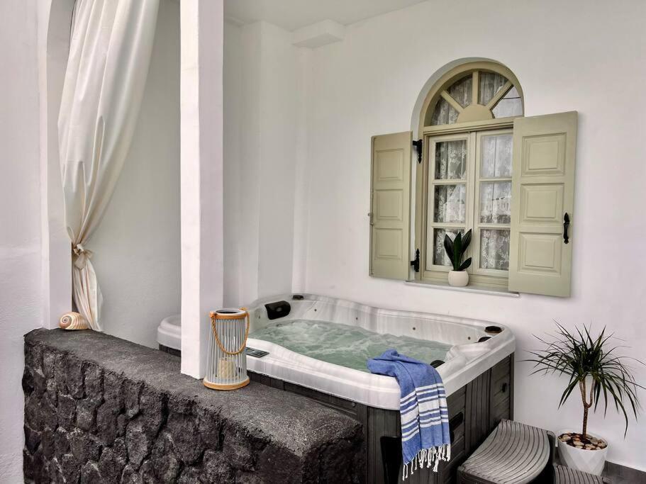 a bath tub in a room with a window at Luxury Vacation Villa Irene with private juccuzi in Fira