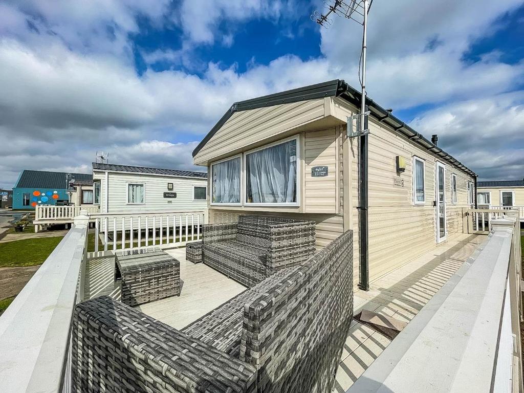 a house with two benches on a deck at Modern Caravan With Wifi At Martello Beach Holiday Park In Essex Ref 29015sv in Clacton-on-Sea