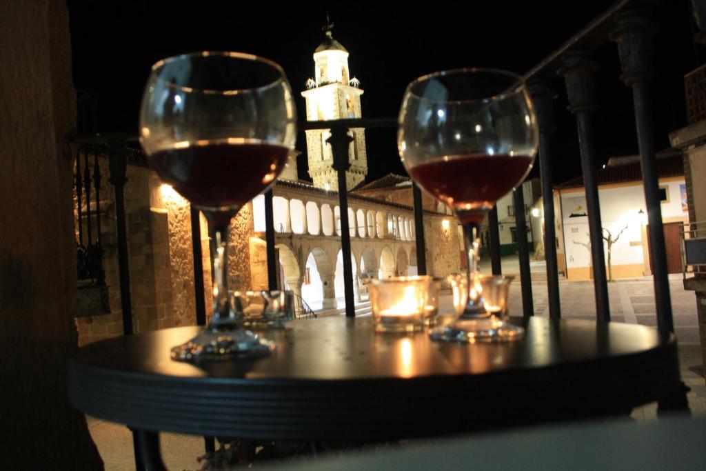 AlmoharínにあるCasa Rural la Plazaの時計塔を背景にテーブルに置いたワイン2杯