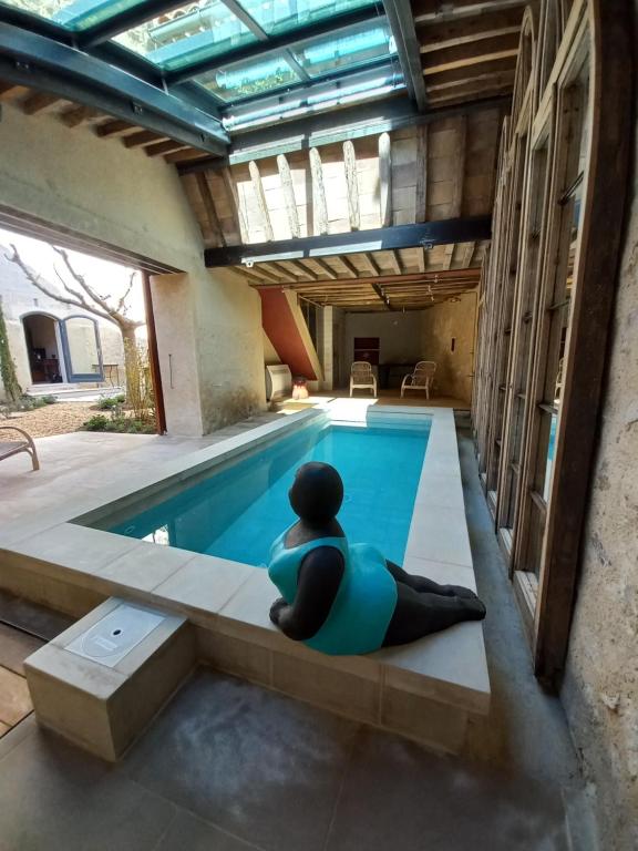 a person sitting on a bench next to a swimming pool at LA CASA DE BOULBON in Boulbon