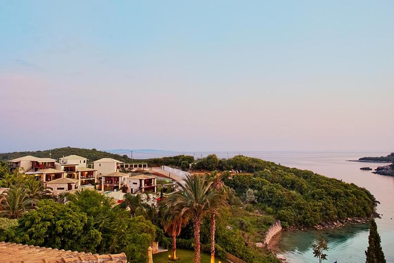 a house on a hill next to a body of water at Ornella Beach Resort & Villas in Syvota