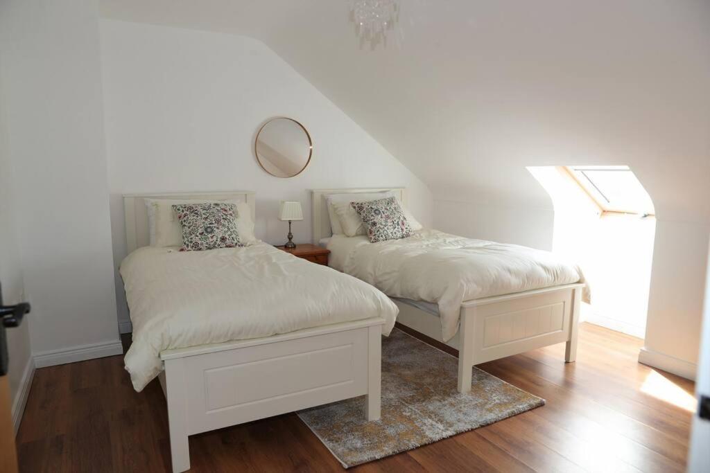 a bedroom with two beds and a mirror on the wall at 4 Castle Court in Killyhevlin