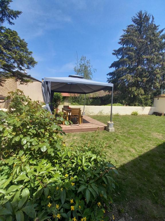 un refugio de picnic con una mesa de picnic bajo un paraguas azul en Gîte des Pleiades, en Villemoirieu