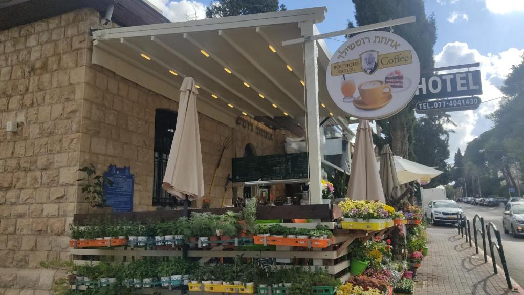 a coffee shop with an umbrella and flowers in front of it at Rothschild Mansion in Haifa