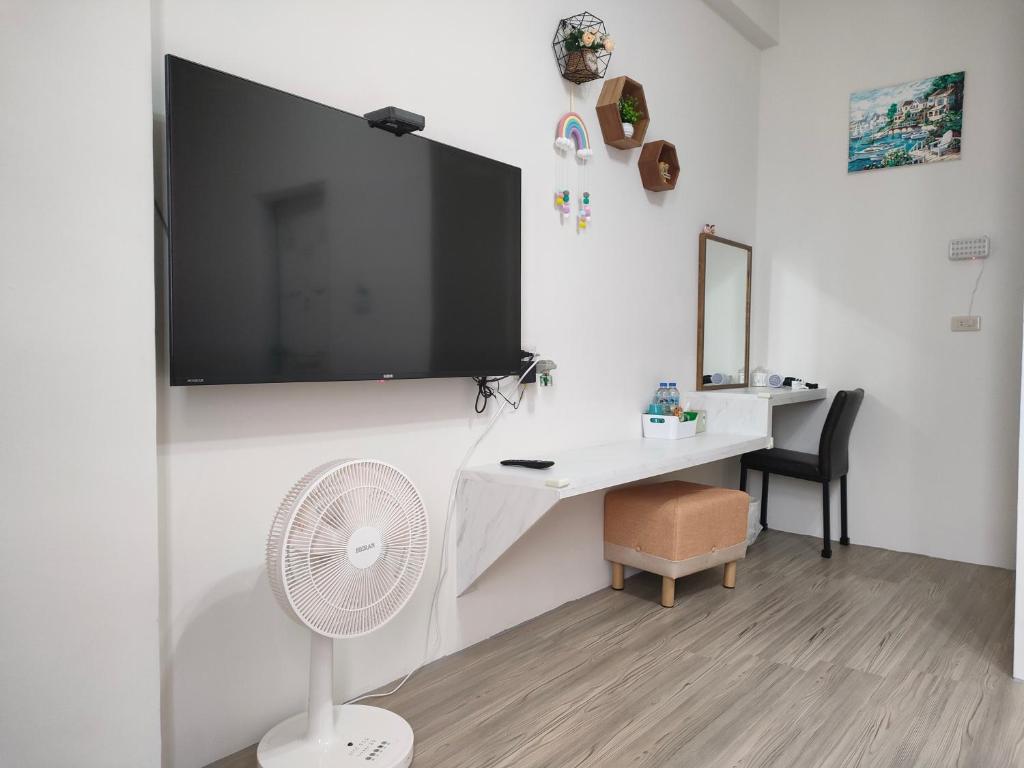 Habitación con escritorio, ventilador y TV en la pared. en 上海民宿, en Chaozhou