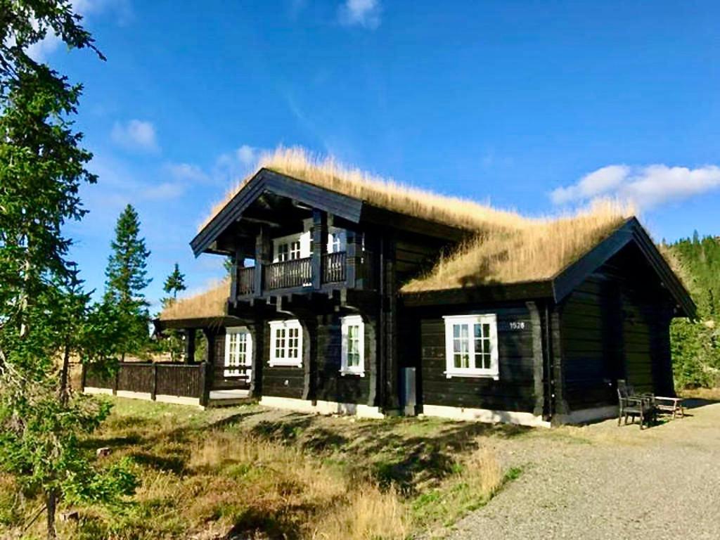 Cabaña de madera grande con techo de hierba en Log cabin on Natrudstilen Sjusjøentrail outside en Sjusjøen