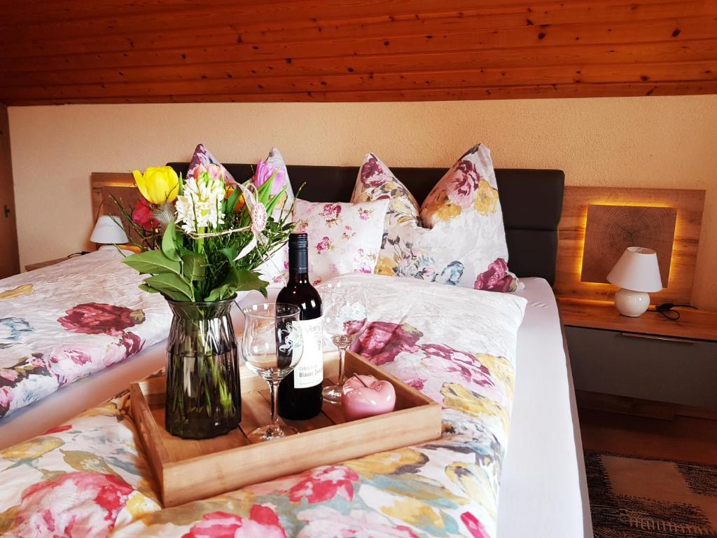 ein Tablett mit Weinflaschen und Blumen auf dem Bett in der Unterkunft Bergbauernhof Rebernig in Lendorf