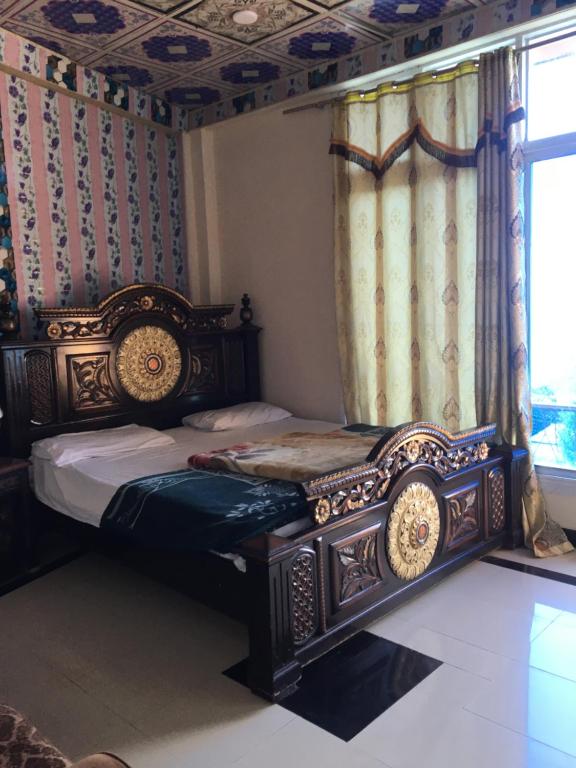 um quarto com uma cama de madeira num quarto com uma janela em Three Star Hotel & Restaurent Malam jabba swat em Malam Jabba