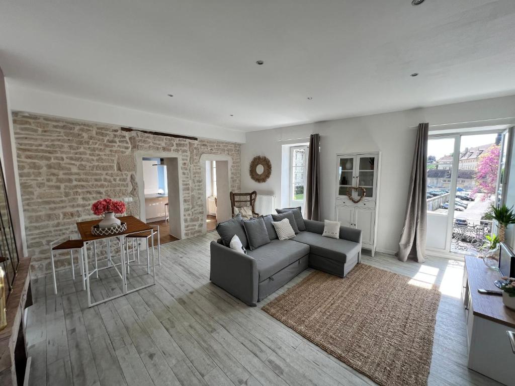 a living room with a gray couch and a brick wall at Détente et vue exceptionnelle à L'appart' de Charles in Dole