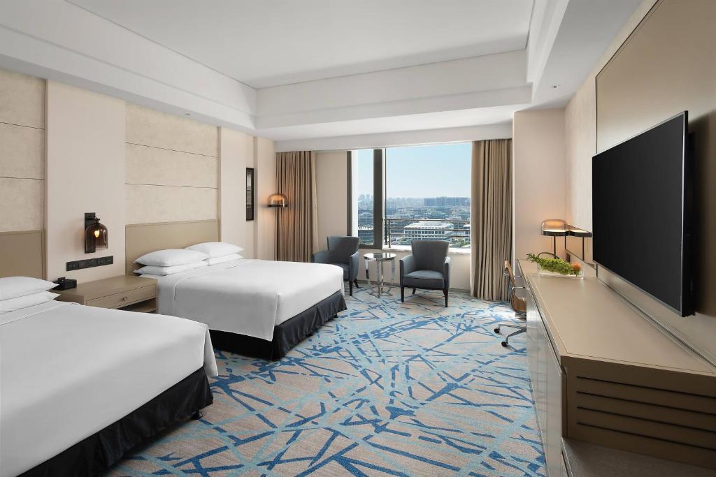 Renaissance Shanghai Caohejing Hotel في شانغهاي: غرفة فندقية بسريرين وتلفزيون بشاشة مسطحة