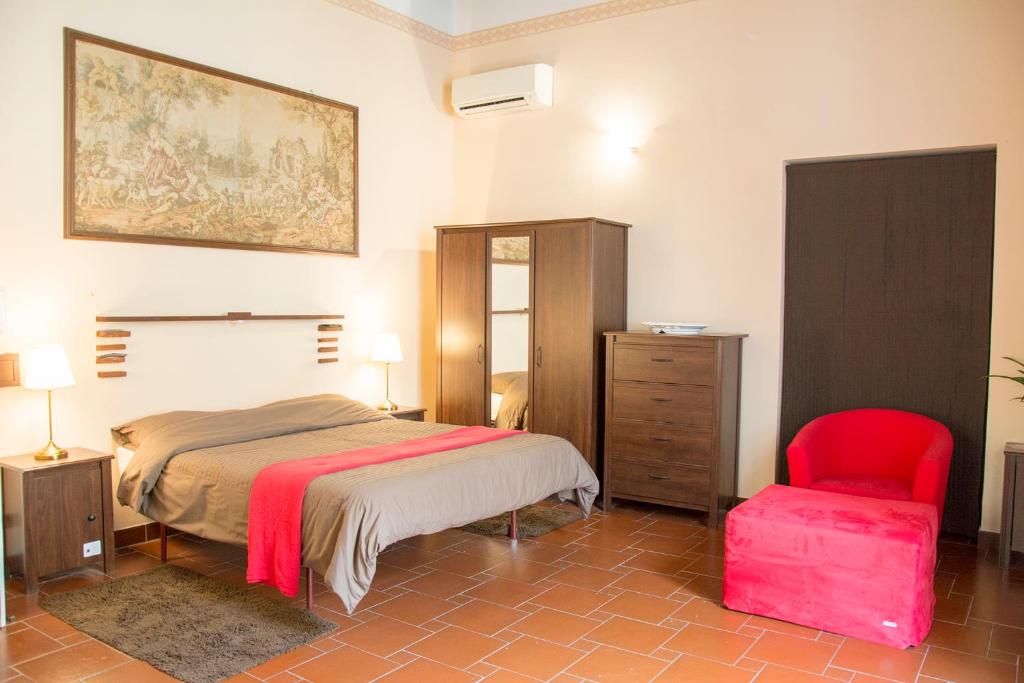 - une chambre avec un lit et une chaise rouge dans l'établissement B&B Peruzzi Rooms, à Civitavecchia