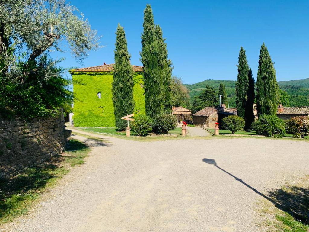 a green building with trees and a dirt road at Locanda di Santantimo in Chiassa Superiore