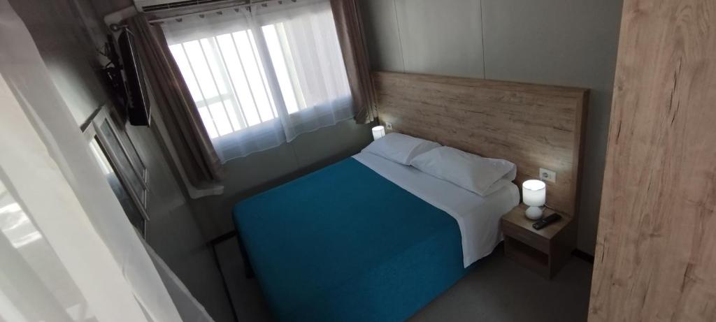 a small bedroom with a blue bed and a window at Tropical Bungalow in Diamante