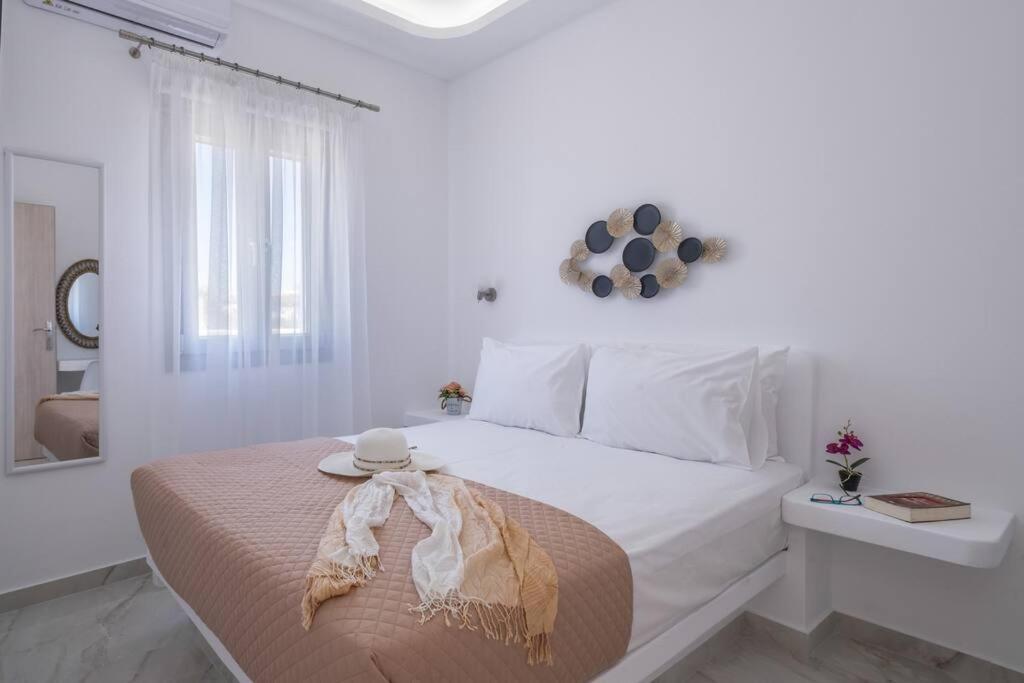 a white bedroom with a bed with a hat on it at Perissa Secret in Perissa