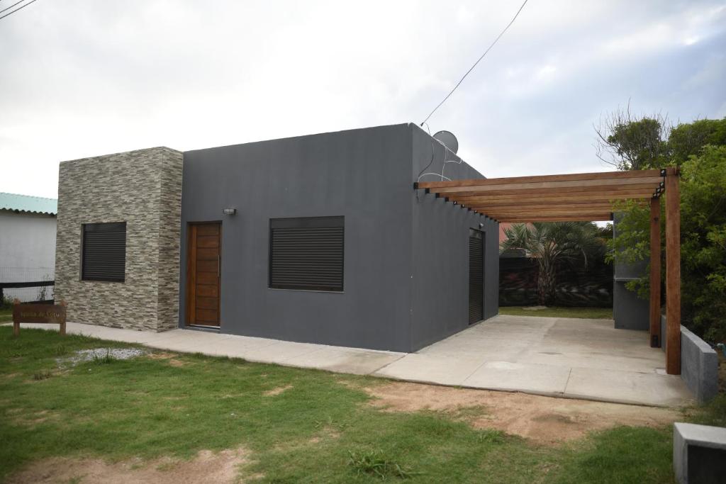 uma casa cinzenta com uma pérgula de madeira em Agüita de Coco em Barra del Chuy
