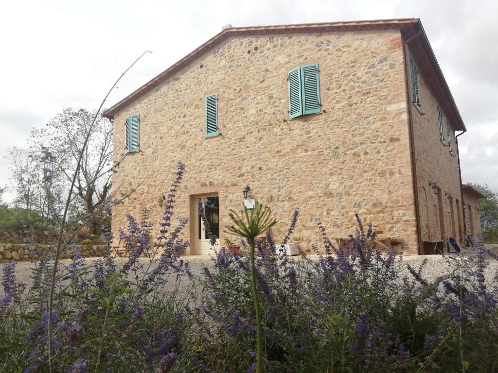 un antiguo edificio de piedra con persianas azules en Podere Stabbiatelli, en Montenero