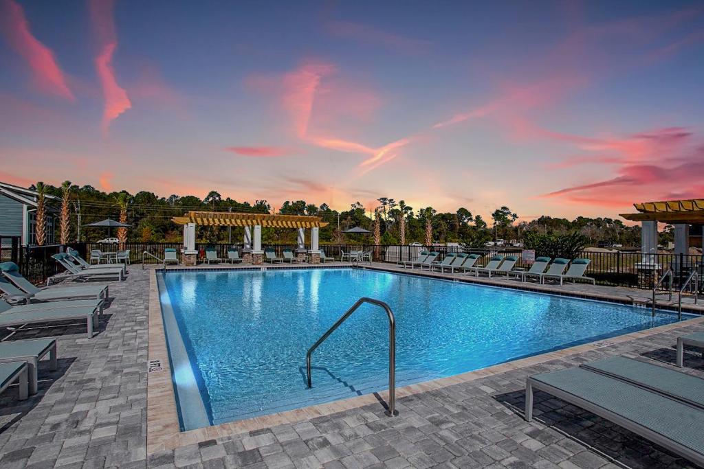 a swimming pool at a resort with chairs and a sunset at "OneKey" Luxury Apt - POOL - 4 Mi to Beach in Daytona Beach