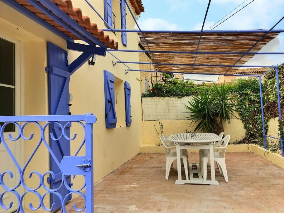 een patio met een tafel en stoelen op een huis bij Bleu Lavande - Coquet appartement ambiance village in Istres