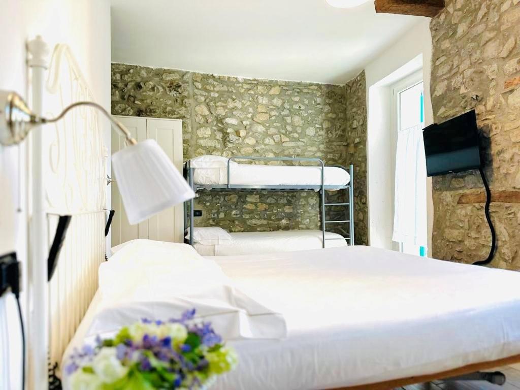 a bedroom with two beds in a room with a stone wall at Casa Caterina in Lezzeno