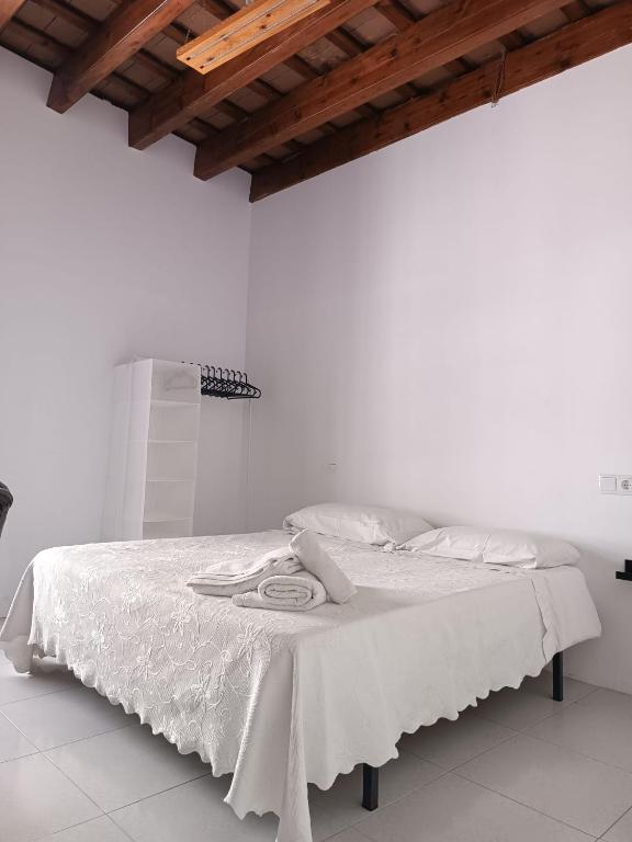 białe łóżko z białą pościelą i drewnianym sufitem w obiekcie Apartamentos Arquillo de Rota w mieście Sanlúcar de Barrameda