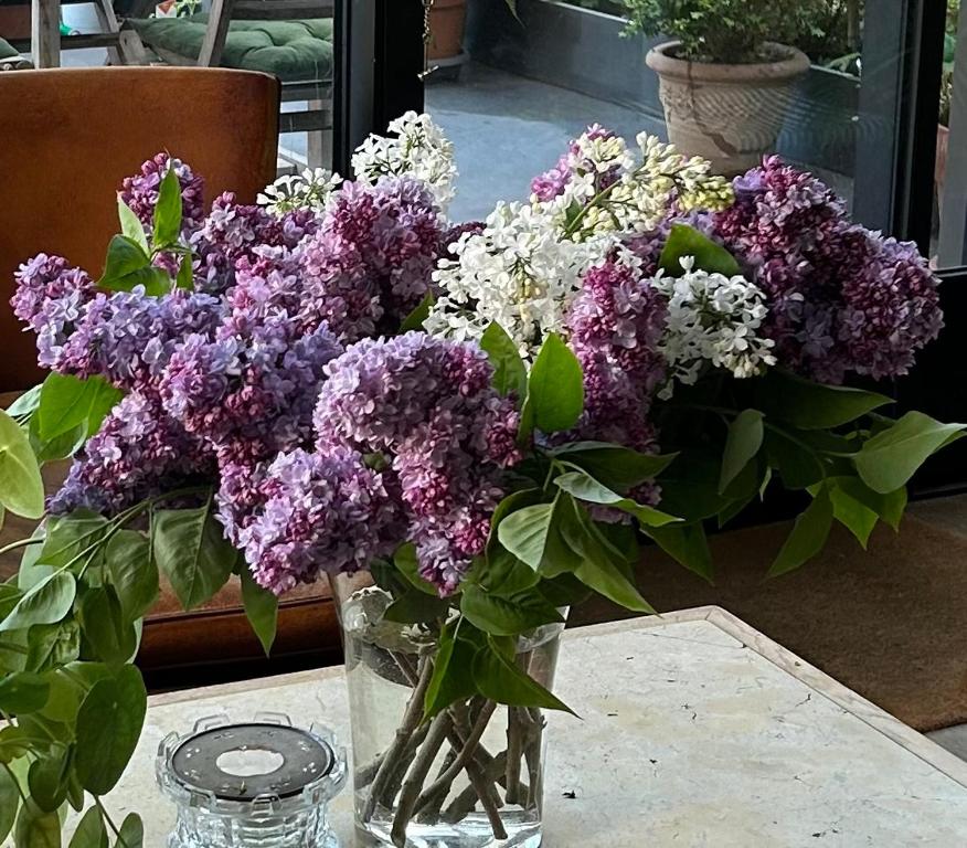 a vase filled with purple and white flowers on a table at Le Jardin Cathedrale in Chartres