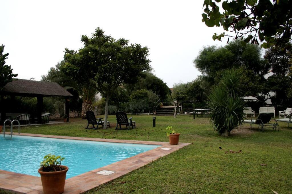 una piscina in un cortile con sedie e tavoli di Casa de campo - Cortijo El Palomar a Alcántara