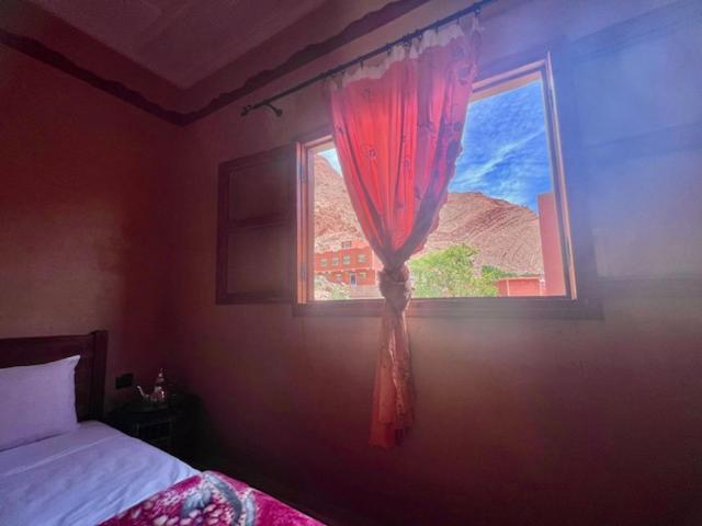 1 dormitorio con ventana y cortina roja en Riad La Fleur, en Aït Baha