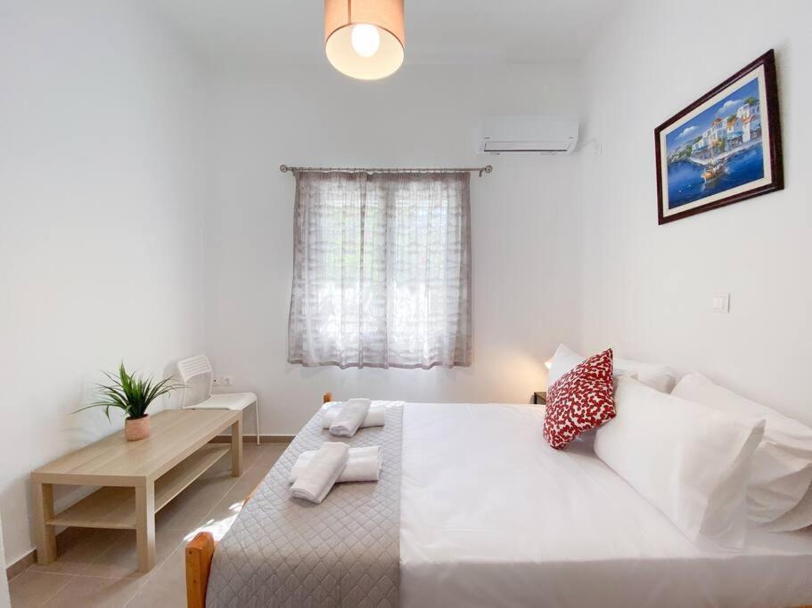 a white bedroom with a large bed and a table at Aquaterra Askeli Poros in Poros