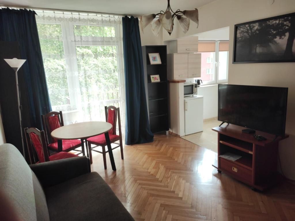 - un salon avec une télévision et une table avec des chaises dans l'établissement Zielony Żoliborz, à Varsovie