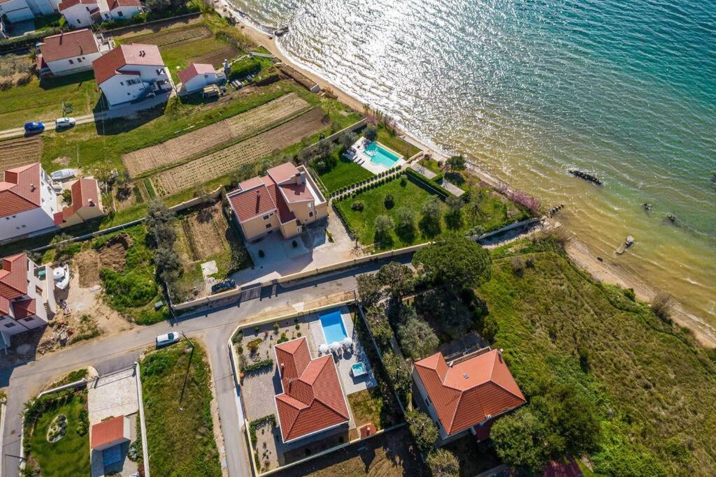 eine Luftansicht eines Hauses neben dem Wasser in der Unterkunft Villa Mattina, with heated pool and jacuzzi in Privlaka