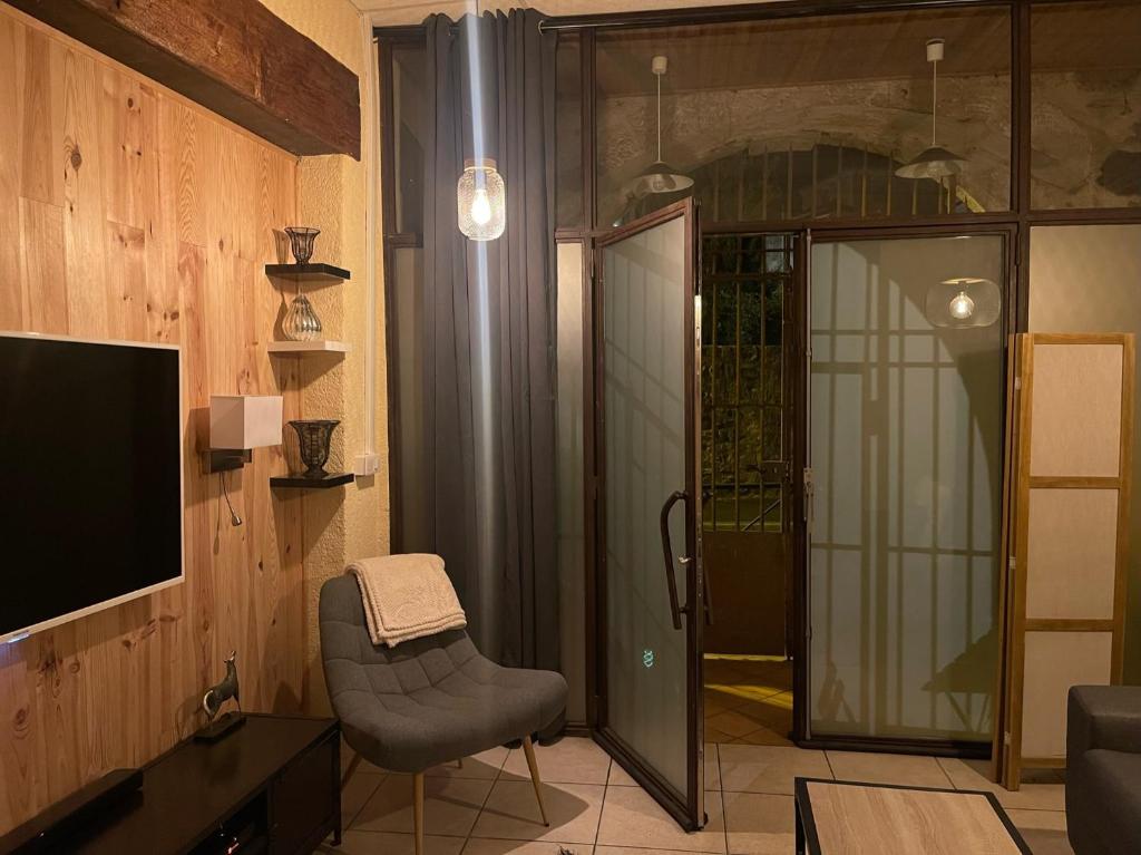 a living room with a chair and a television at POPPY appartement de charme à 2 min centre-ville in Figeac