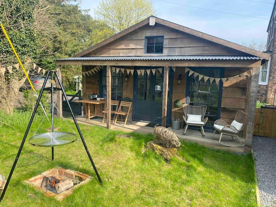 una pequeña casa con una mesa y sillas en un patio en Cosy cottage and lodge, near York, 