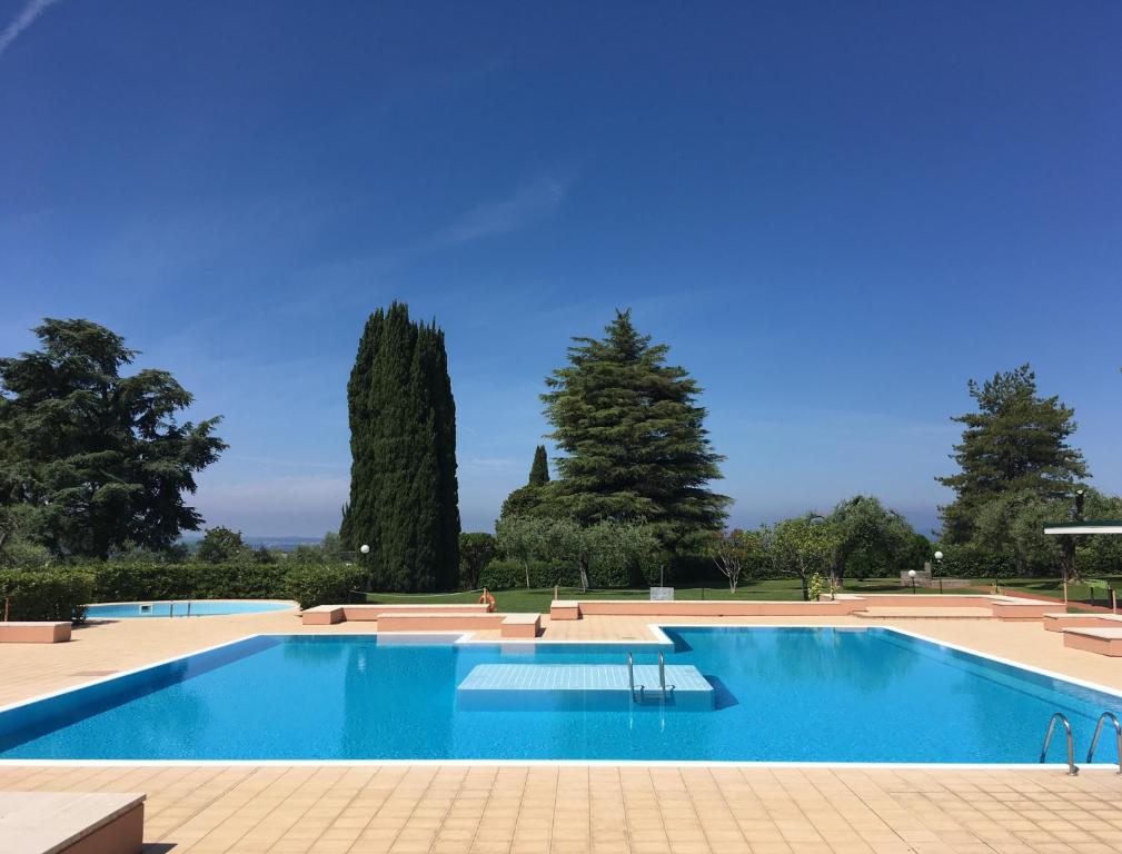 a large swimming pool with trees in the background at Appartamento Noal in Bardolino