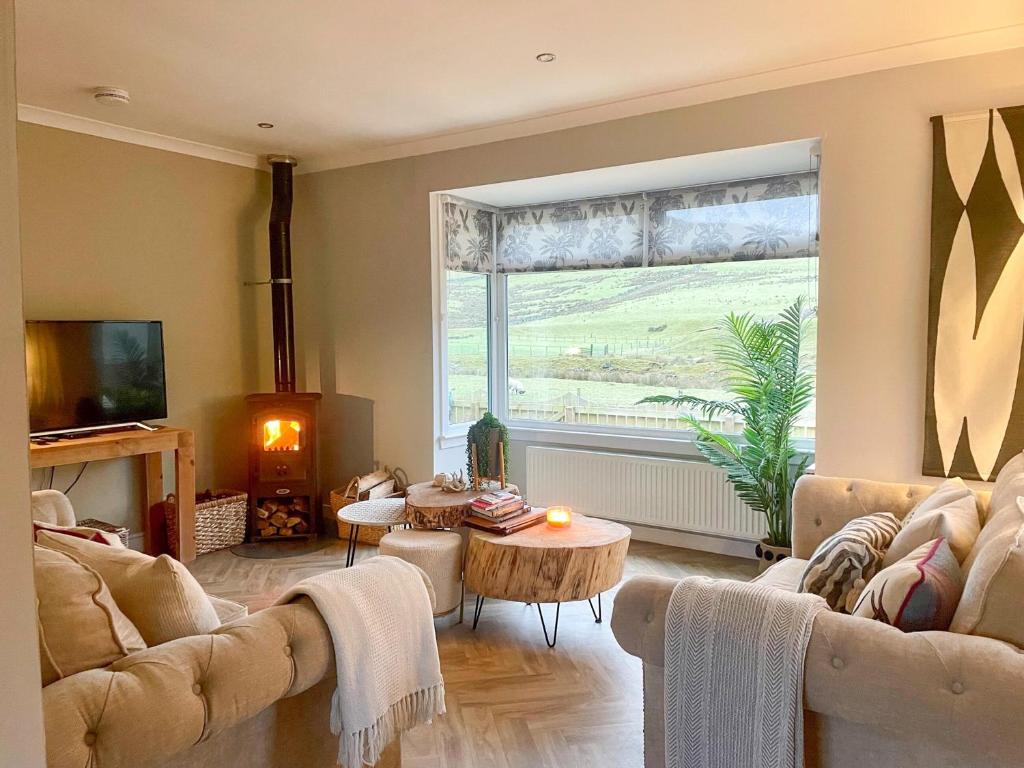 a living room with a couch and a large window at Mossdale Cottage in Dalmellington