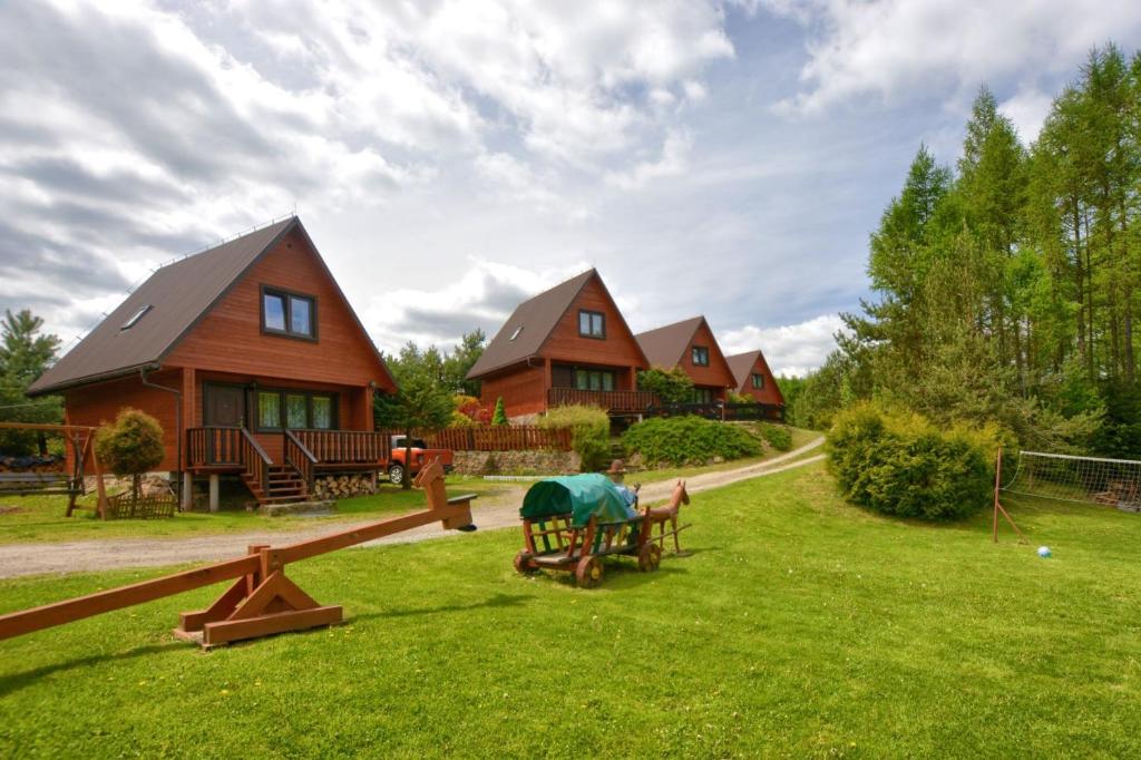 a group of houses in a yard with a house at Domki Zacisze nad wodą in Baligród